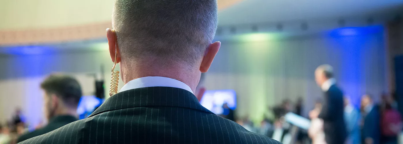 Close-up of a bodyguard with an earpiece during executive protection training at Pacific West Academy, ensuring safety in a high-profile event